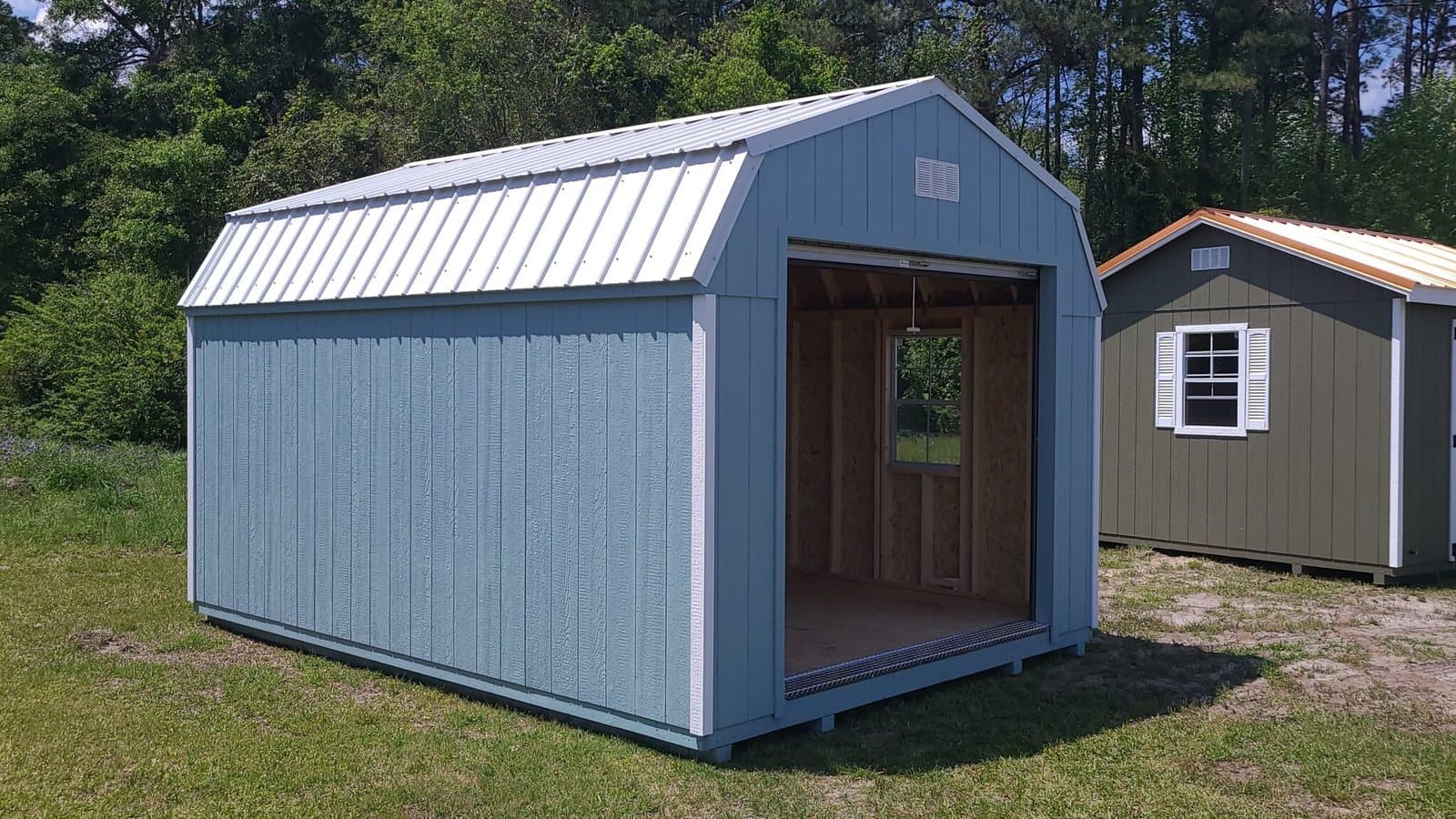 A 12x16 blue lofted barn portable building on a grass lot in Walterboro, SC